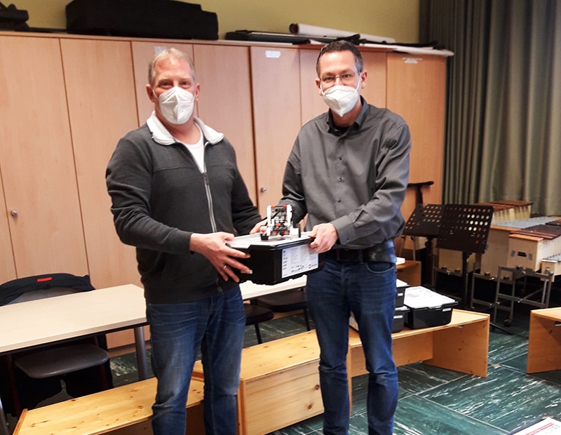 Zwei Männer mit Masken präsentieren ein mobiles Wiegesystem von Pfreundt in einem Büro.