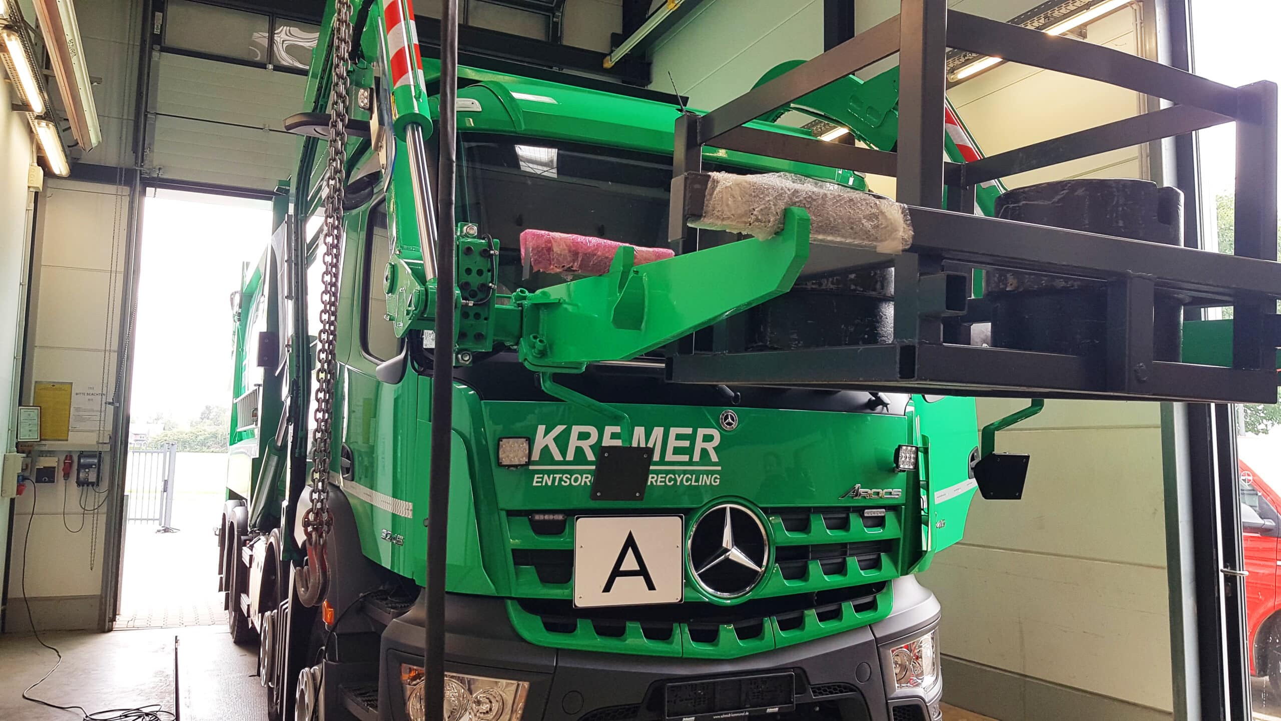 Grüner Lastwagen mit Wiegesystem von Pfreundt in einer Werkstatt, bereit für mobile Gewichtsmessungen.