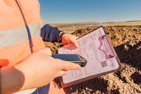 Mitarbeiter bedient mobiles Wiegesystem auf Baustelle mit Tablet und Klemmbrett.