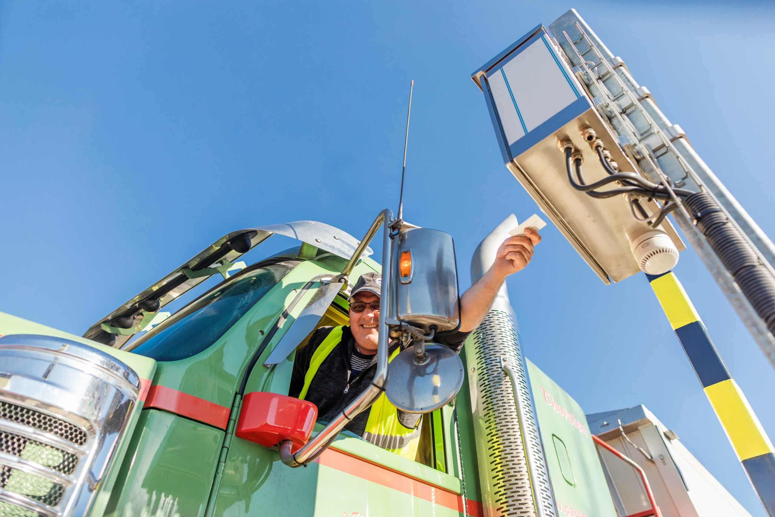 Lkw-Fahrer nutzt Pfreundt Wiegesystem an einer mobilen Station unter blauem Himmel.