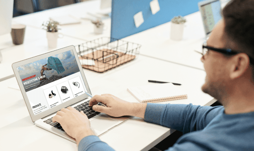 Person arbeitet am Laptop mit Pfreundt-Webseite über mobile Wiegesysteme für Bagger, Radlader und mehr.