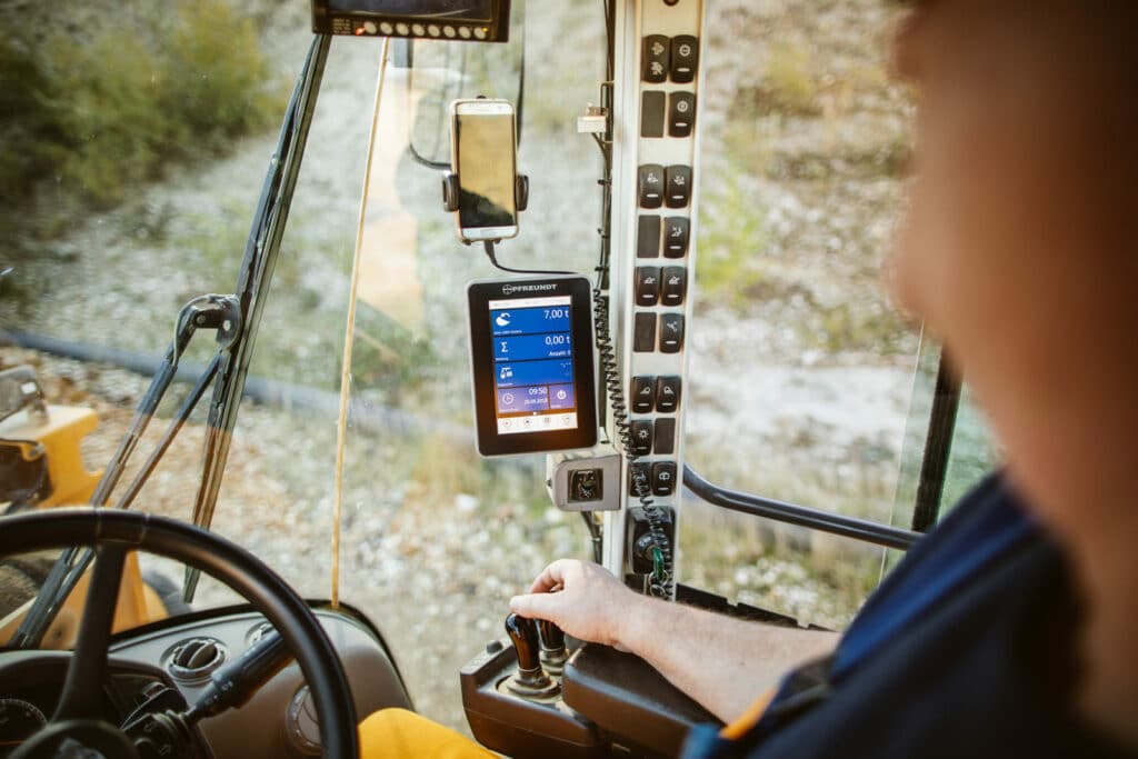 Cockpit eines Fahrzeugs mit Pfreundt-Bordcomputer für mobiles Wiegen, Fahrerhand am Hebel.
