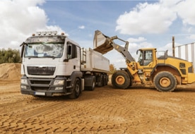 Radlader belädt LKW auf Baustelle, zeigt mobile Wiegetechnik von Pfreundt für effizienten Materialtransport.