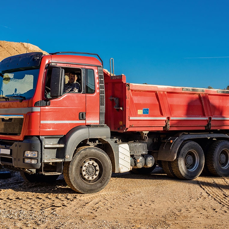 Roter Lkw auf Baustelle mit Pfreundt mobiler Wiegesystem-Technologie für genaue Gewichtsbestimmung unterwegs.