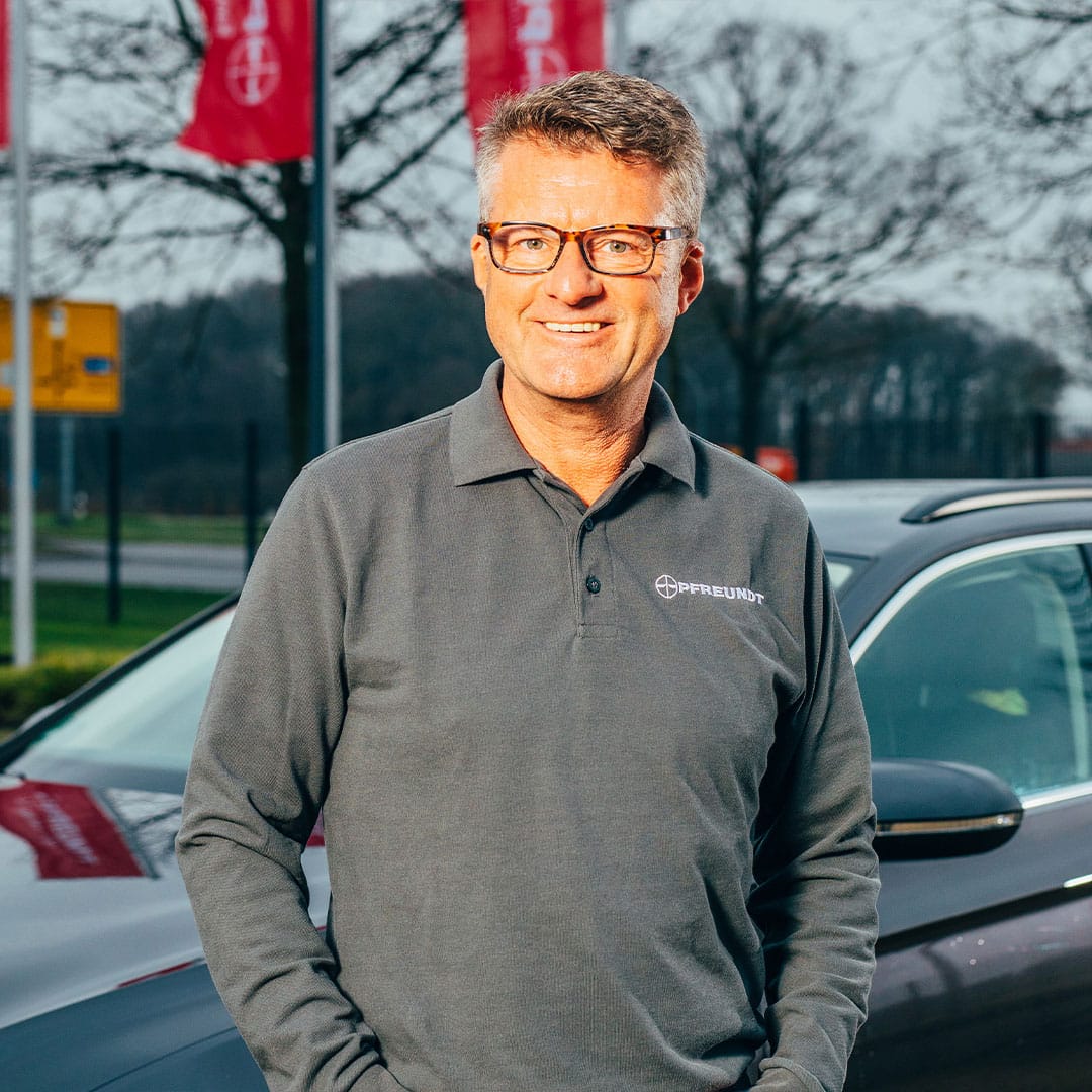 Person im Pfreundt-Shirt steht vor einem Auto. Firma Pfreundt: Spezialist für mobile Wiegesysteme.