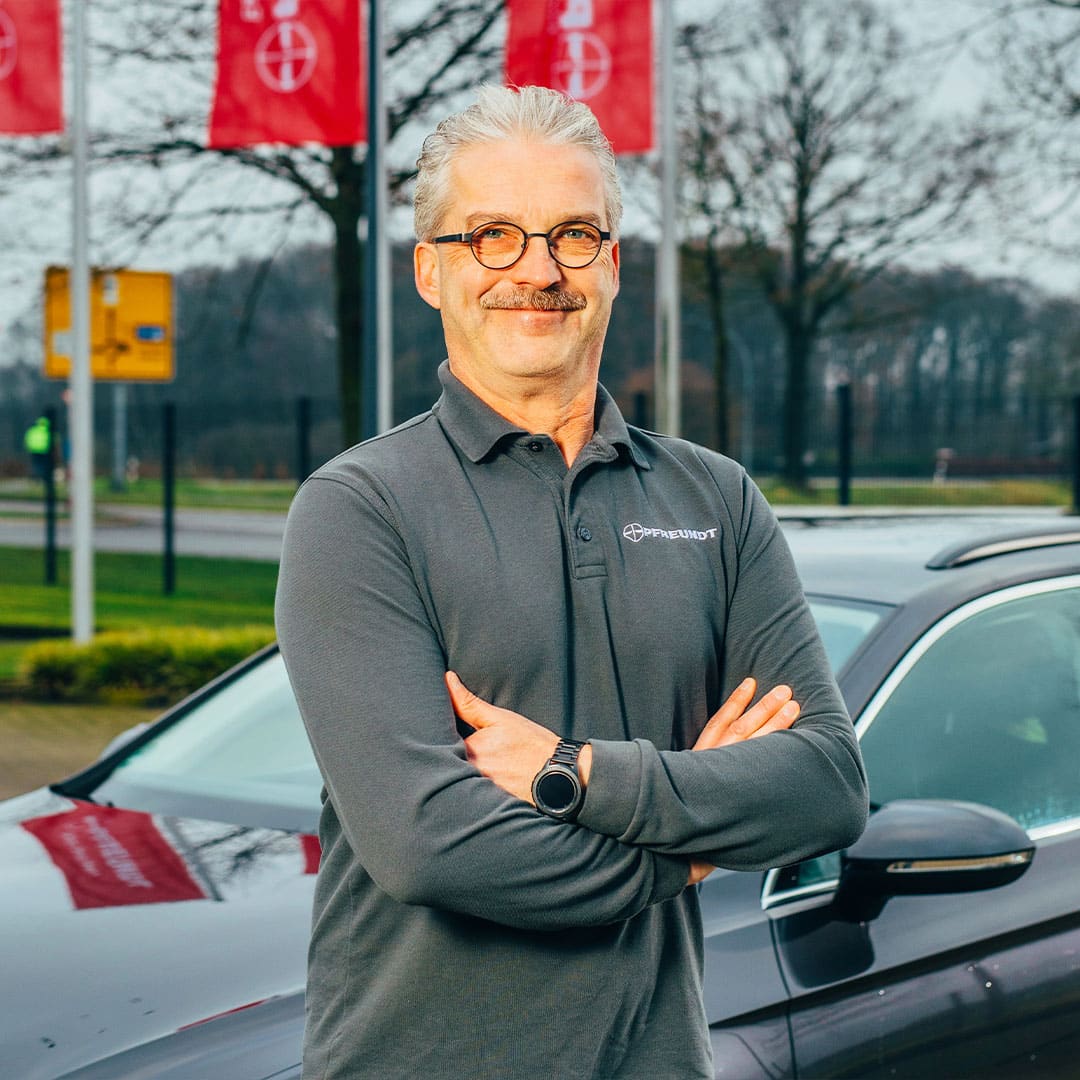 Mann in Pfreundt-Poloshirt vor Firmengebäude, bietet mobile Wiegesysteme für Bagger, Kräne und Radlader.