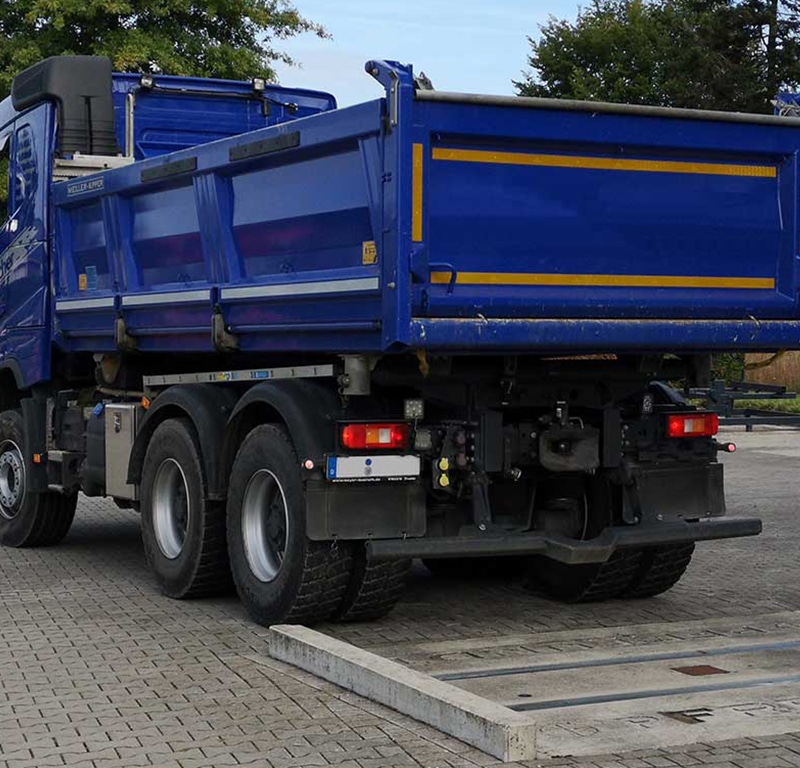 Blauer LKW auf mobiler Achswaage von Pfreundt für exakte Gewichtserfassung, ideal für Bau- und Logistikunternehmen.