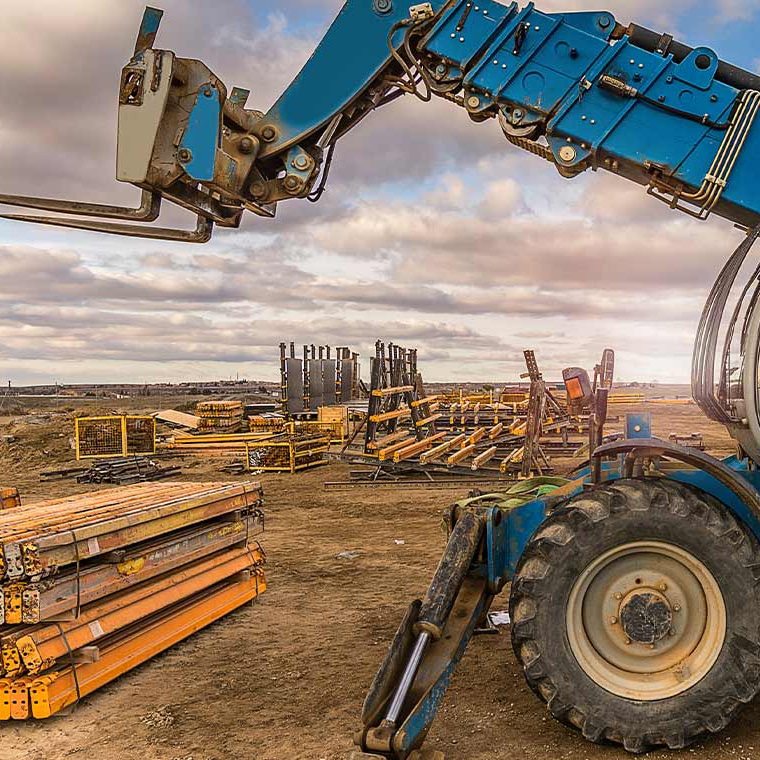 Blauer Radlader hebt Baumaterialien auf einer Baustelle, mit Pfreundt mobiler Wiegetechnik.